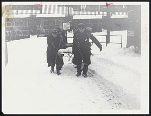 Woman who collapsed while walking in snow is carried to ambulance by police. This happened on Tremont St. + Broadway.