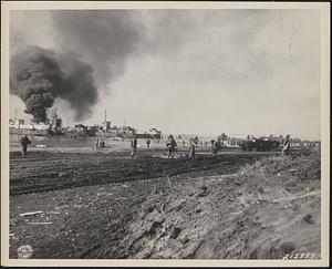 An LCI burns while troops and equipment come ashore at the new U.S. Fifth Army beachhead near Anzio, Italy