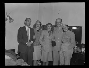 Mixed gender group standing in bedroom, some in uniform