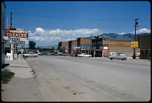 Small-town street with mountains in background, likely Montana