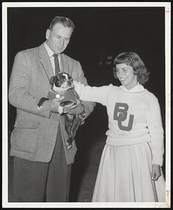 Boston University Football coach Steve Sinko holds Ch. Flash Again Boots II, with cheerleader Jo Scarcella of Needham at last night's rally at the Arena. The terrier was loaned to BU for today's game with Boston College. by Mr. and Mrs. Eugene Riordan of North Reading. Fumbles, the regular mascot is sidelined with the flu.