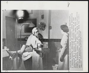 Emergency Treatment--A doctor, (partly obscured at rear), gives emergency treatment to a young lady tornado victim at the Susan B. Allen Memorial Hospital here. With the town's electric power cut off, the only illumination was from a gasoline lantern hanging from the ceiling.