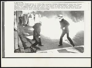 Fiery Battle in Tokyo – Two helmeted student demonstrators stand near flames of exploding firebombs during clash with riot police at Tokyo’s Kamata railway station Sunday. In background are the riot police with metal shields. The clash came about as the students protested Prime Minister Eisaku Sato’s visit to the United States this week.