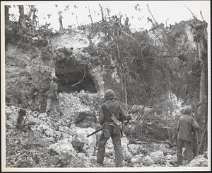 Marine infantrymen warily approach an enemy cave on Guam