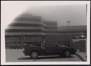 Boy standing in front of a car in a parking lot