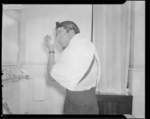 Joe DiMaggio combs his hair in hotel room