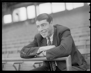 Joe DiMaggio in suit sits in stands at Fenway