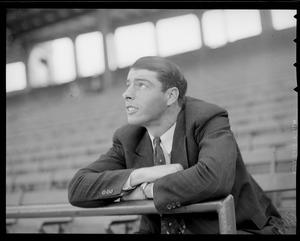 Joe DiMaggio in suit sits in stands at Fenway