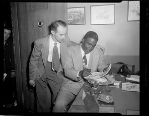 Jackie Robinson signs autograph for fan