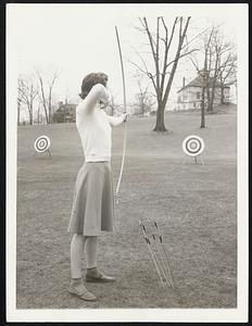 Anne stands erect but not stiffly as she takes sight of the target before releasing her arrow. Note the upraised position of her right arm.