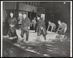 Flooded Peabody-Boats replaced cars in Peabody as water rushed through a 40-foot hole in a dam and flooded two square miles in the heart of the city. Bottom. Civil Defense workers tow their boat on the way to a rescue.