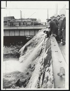 Firemen Flushing Snow which clogged Fort Point channel after thousands of tons had been dumped from trucks. Summer street bridge in background. Fireboat Matthew J. Boyle also was used to clear the channel.