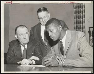 Now It Is Official- Bill Russell signs contract to play with the Celtics. Co-owner and president Walter Brown (left) and co-owner Lou Perini witness the signature of Russell, who starred with the U. S. Olympic basketball champions after brilliant career with San Francisco's national intercollegiate titlists.