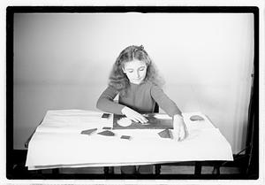 A girl matching fitting shapes in a puzzle
