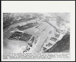 Flooded Out--Logan High School, left, is surrounded by waters of the flooding Guyandotte River today as rampaging stream neared crest. Bridges at upper right span stream bed, but go nowhere, ending in high water.