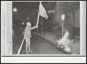 Disturbance at Moratorium--A demonstrator waves a Viet Cong flag as he watches a police motor bike burn during a confrontation between antiwar demonstrators and police in Washington tonight.