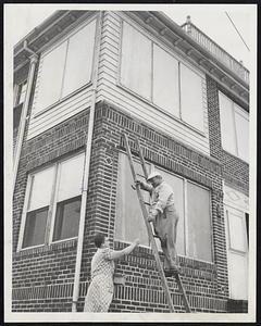 Boarding All Windows of his home at 187 Winthrop Shore Drive, Winthrop, as a hurricane precaution is Walter Mussucco. Handing him nails is Margaret Deveau, a neighbor. The Winthrop shore area was hard hit by the hurricane of Aug. 31.