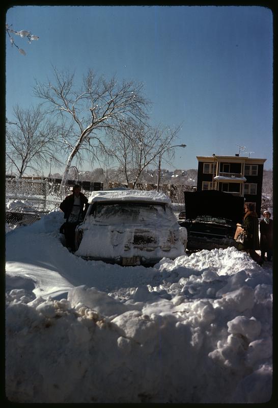 Snow covered car behind a snowbank