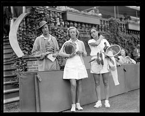 Two tennis players standing next to a woman