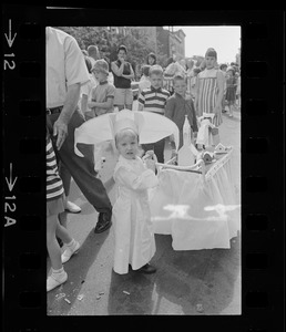 Girl dressed as the Flying Nun and standing with her decorated carriage at Bunker Hill Day Parade