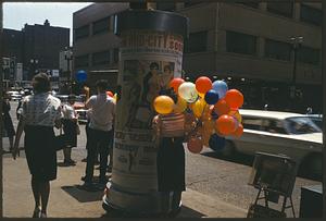 Woman on sidewalk holding balloons, St. Louis, Missouri