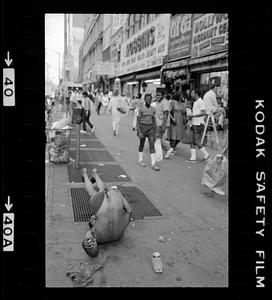 A man on the ground of a busy sidewalk