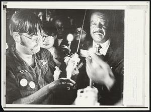 Card burning at Kent State - Student Tim Butz (L) holds a candle to a draft card at the close of a Monday night service at Kent State University in memory of four students killed at the school May 4 in a confrontation with Ohio National Guardsmen. The Rev. Ralph Abernathy, president of the Southern Christian Leadership Conference, who participated inthe burnings, is at right.