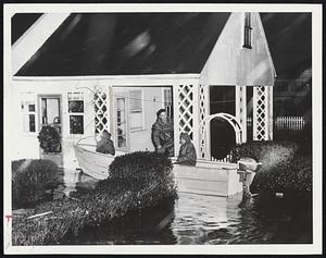 Volunteer rescue workers sail to porch of home on Packard Ave., Hull, to aid a family stranded by flood waters from northeast storm.