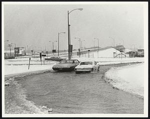 Flooded Roadway at entrance to the Massachusetts Pike in Allston was partially blocked by stalled car on right.