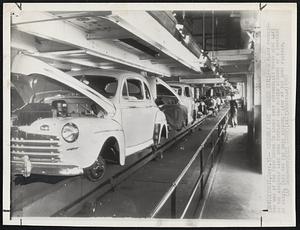 Detroit – Assembly Line Stands Still – A plant protection man at the Ford Motor Co looks over automobiles which were left on the assembly line when the plant was closed because of shortage of parts. This was the main assembly line at the huge factory.