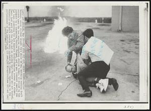 One Fire Put Out, Other Burns--Walter Skinner, whose clothes caught fire while he was watching burning draft records near the Los Angeles induction station today, is rolled on the pavement by a companion, Charles Friend, and a man (nearest camera) who had been picketing the Los Angeles Herald-Examiner across the street. Their fast work put the fire out so quickly that Skinner was not burned. Meanwhile the draft records were consumed by flames, resulting in the postponement of the induction of 231 men.