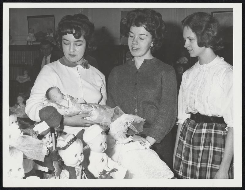 Annual Doll Display at Roslindale High School is inspected by three students before the toys are distributed to unprivileged children. From left are: Jacqueline Brienza, 16, Rita Colley, 15, and Edith Carrigan, 15.