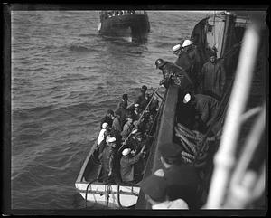 A group of people in a boat by the side of a larger ship