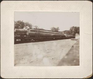 Train hauling flatbed, logs for ship masts