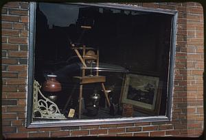 Window in brick wall displaying tools, framed picture, and other objects, Boston