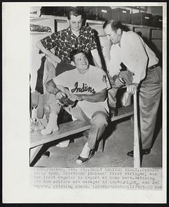 Early Arrives Early.. Pitcher Early Wynn, Cleveland Indians' first stringer, was the first regular to report at camp here. Watching him don uniform are manager Al Lopez, right, and Mel Harder, pitching coach.