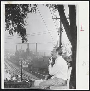 Sitting on Front porch of home in Pittsburgh, Pa., is Frank Studnicki. He has worked 35 years in the open hearth furnace of Jones & Laughlin steel company plant. Studnicki is looking out over the idle plant in Pittsburgh's famed steel valley below. Steel workers went on strike after contract expired.