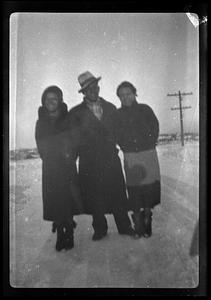 One man and two women stand in the snow