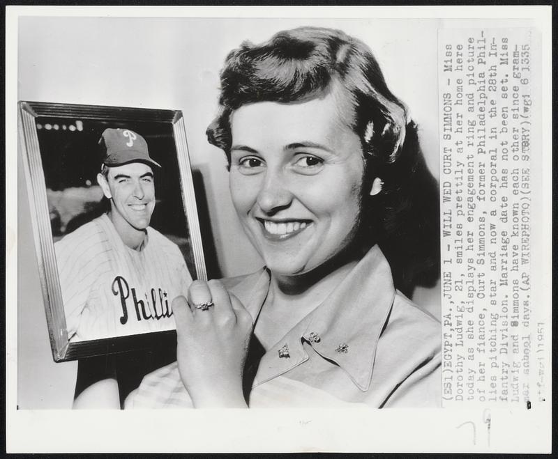 Will Wed Curt Simmons- Miss Dorothy Ludwig, 21, smiles prettily at her home here today as she displays her engagement ring and picture of her fiance, Curt Simmons, former Philadelphia Phillies pitching star and now a corporal in the 28th infantry Division. Marriage date has not been set. Miss Ludwig and Simmons have known each other sins grammar school days.