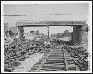 Roads to Nowhere- Tracks of the New Haven Railroad at Putnam, Conn., end in a twisted mess under a ruined bridge across the Quinebaug river. Now a meandering stream, the fury of the river a few days ago cut the town in half and demolishes several mills. A topped building is in right background and several freight cars are tossed at left. Repair to tracks is expected to take weeks.