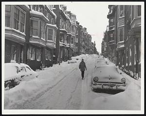 At right, lone pedestrian walks past buried cars on narrow, snowclogged Pinckney St. on Beacon Hill.