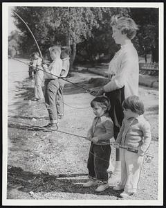 Practicing for Fish Rodeo- Ann and Elizabeth Franklin, 2 1/2year-old daughters of Mr. and Mrs. Earl Franklin of Jamaica Plain, practice for the Boston Park Department-Boston Traveler fishing Rodeo to be held at Jamaica Pond next Thursday. With them is their babysitter, Maridith Matthews of Jamaica Plain. Boys and girls 15 and younger are eligible.