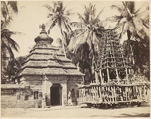 View of entrance gate to unidentified temple and large wooden structure on wheels