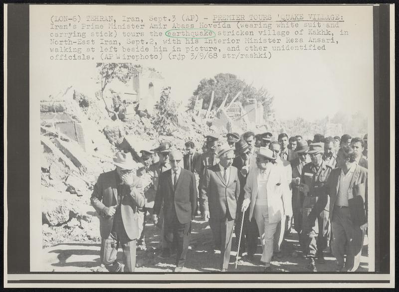 Premier Tours 'Quake Village: Iran's Prime Minister Amir Abass Hoveida (wearing white suit and carrying stick) tours the earthquake stricken village of Kakhk, in North-East Iran, Sept. 2, with his Interior Minister Reza Ansari, walking at left beside him in picture, and other unidentified officials.