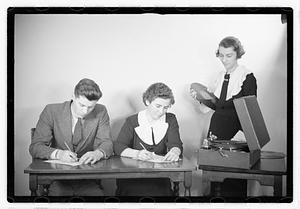 A man and a woman listening to a record, possibly taking a test
