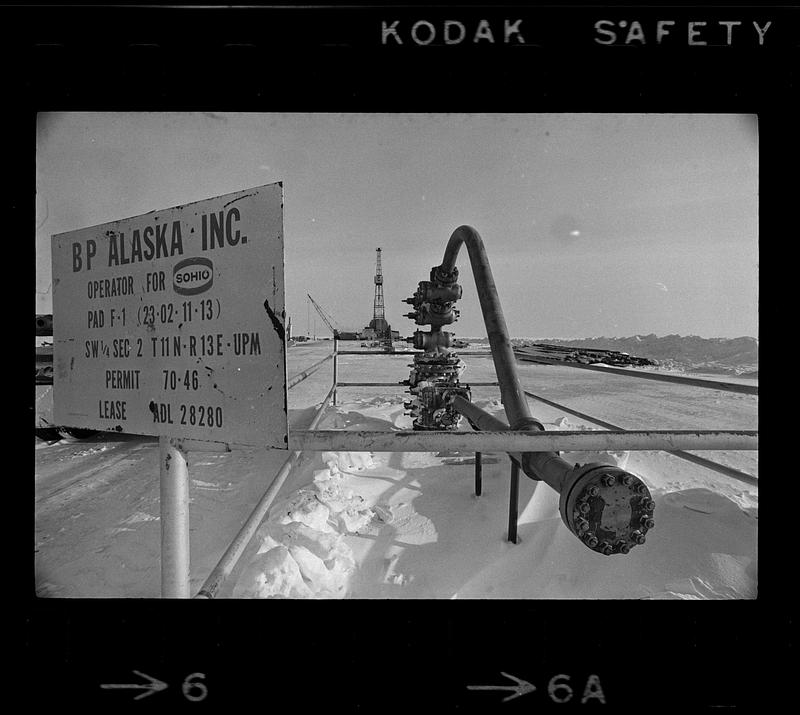 BP Alaska oil pipe, derrick in background, sign in foreground