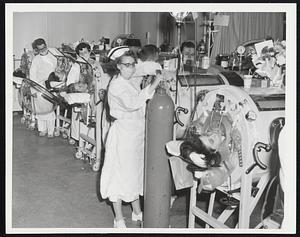 Beehive of Activity--This is part of the scene in the respirator ward of the Haynes Division of Infectious Diseases of the Massachusetts Memorial Hospitals. Patients confined to iron lungs require constant attention. Nurses who specialize in their care are on duty in the war and team with other professional help.