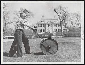 Musically Speaking, the theme might be, "Merrily We Roll Along," but William Kelliher and John John of Cambridge are not concerned with lilting lyrics. They are teaming up on the spring task at Longfellow House, Cambridge, of flattening winter's bumps on the lawns. Rolling presses frostheaved grass back into the soil and prepares the lawn for mowings to come.