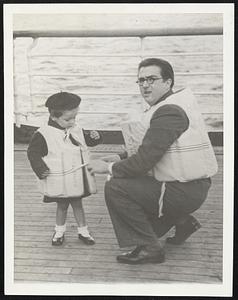 Lefe Savings Drills for the Kiddies War is serious business even for passengers on neutral ships and includes even the children. Here is Chief Steward Raymond Feuerstake, fitting a special size life preserver on a child during the Atlantic crossing of the U.S. liner Manhattan. The ship docked in New York Oct. 22.