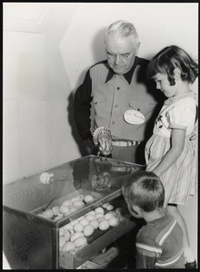 Eastern States Exposition. Mass. State Building. Bill Monehan of the Mass. Turkey Growers Association showing Karren Cote of Keene, N.H. and John Niedzwick of New Britian, Conn how the turkeys break out of their shells. Mass. Turkey Growers Assc. display.
